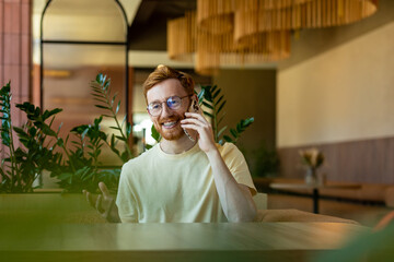 Bearded man having conversation on mobile in cafe at table