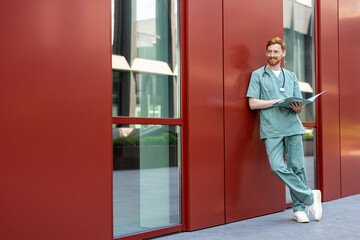 Man doctor in scrubs outdoors with open records folder