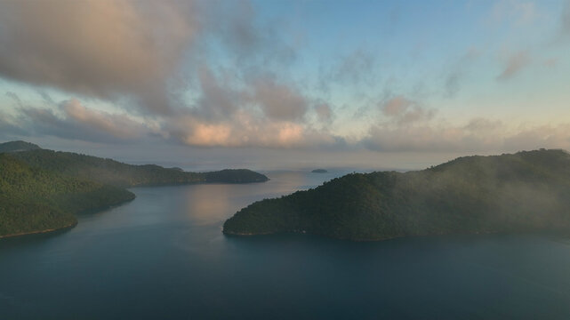 Aerial view of emerald islands nestled in tranquil waters, kissed by the soft glow of dawn, creating a serene coastal panorama, Paraty, State of Rio de Janeiro, Brazil.