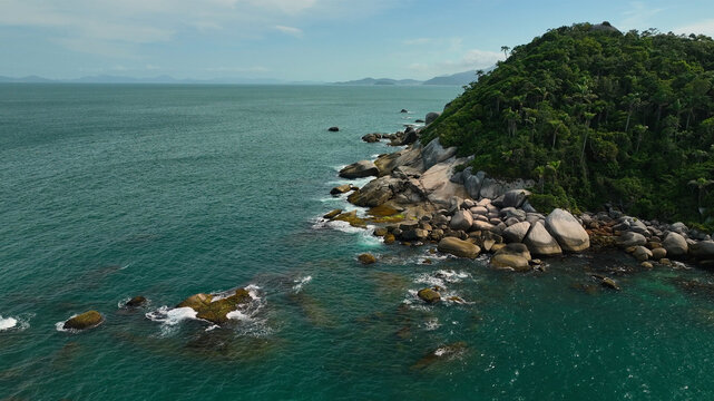 Aerial view of the rugged coastline where the verdant rainforest meets the turquoise sea, creating a stunning contrast of colors and textures, Paraty, State of Rio de Janeiro, Brazil.