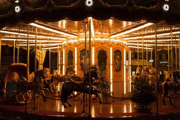 Illuminated vintage carousel at night in a city square © Wirestock