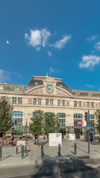 Monumental facade of Gare de Toulouse-Matabiau timelapse hyperlapse, featuring a clock, big windows and flags. The central railway station of Toulouse, France, under cloudy skies with road traffic