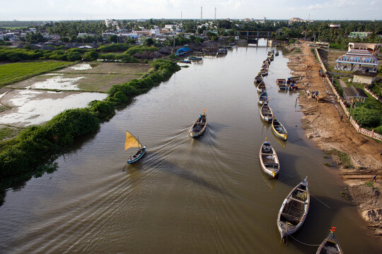 Yanam, India - 03 October 2010: Aerial view of boats glide along the Coringa River, contrasting with the lush green fields and the dusty riverbank settlements.