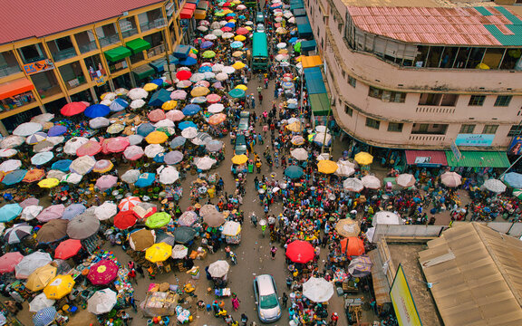 Accra, Ghana - 23 March 2024: Aerial view of Makola Market's vibrant chaos, where a mosaic of colorful umbrellas and bustling crowds converge, creating a lively tapestry of commerce and community.