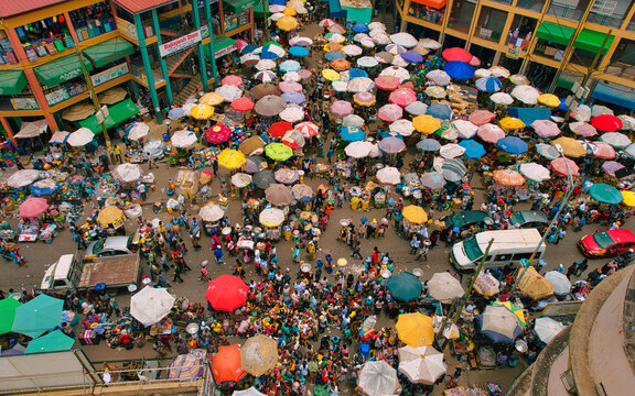 Accra, Ghana - 23 March 2024: Aerial view of Makola Market's bustling scene, where a vibrant tapestry of colorful umbrellas creates a kaleidoscopic effect over the crowded marketplace.