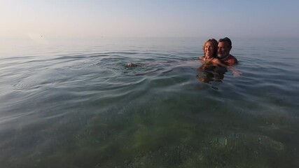 Mature couple embracing in calm ocean water - Powered by Adobe