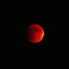 A deep red moon with a shadowed area on one side floats against a dark, empty background