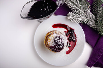 pancakes with blueberry jam in white plate decorated Christmas tree, delicious dessert for breakfast in winter