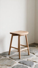 Small curved wooden stool on stone tile floor in soft natural light