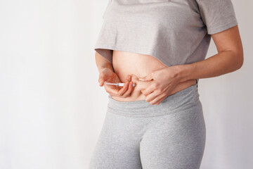 faceless woman giving herself an injection in her stomach. weight loss, diabetes