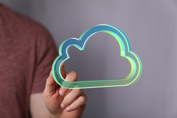 Hand holding a digital cloud icon, representing cloud computing, data storage, and network...