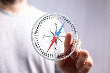 Stock photo of a hand interacting with a digital compass, symbolizing guidance and direction.
