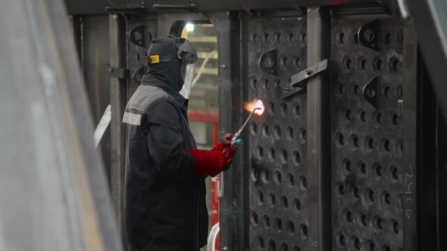 Worker in protective gear cutting metal with an oxygen-propane torch
