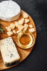 Delicious cheese platter with honey and herbs on wooden board
