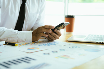 A businessman analyzing financial charts and documents at the office desk, using reports, graphs, and strategy planning for investment success.