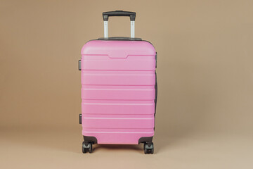 Pink travel suitcase standing upright on neutral background, concept travel luggage and vacation gear