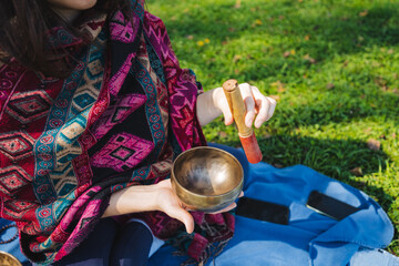 Imagine a woman playing a singing bowl outdoors, embodying meditative tranquility. She immerses...