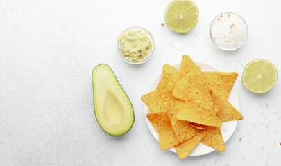 Nachos with avocado, guacamole, lime and salt on white table