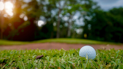 Golf ball is on a green lawn in a beautiful golf course with morning sunshine.