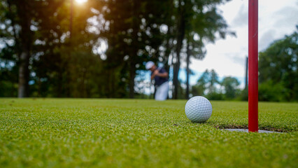 Golfer putting ball on the green golf, lens flare on sun set evening time.