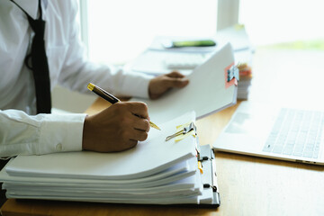 A businessman organizes and reviews stacks of documents with colorful clips on a desk, symbolizing paperwork, office work, and management.