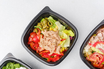 Assorted fresh salads in black containers with gourmet ingredients for meal prep or healthy catering concept