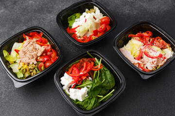 Assorted fresh salads in black containers with gourmet ingredients for meal prep or healthy catering concept