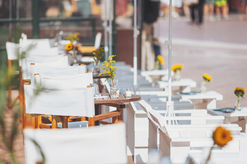 Cozy outdoor seating at a sunny cafe adorned with fresh flowers creating a vibrant atmosphere for relaxation and dining in a bustling urban setting
