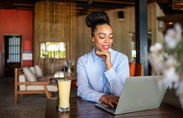 Happy freelancer enjoying a nutritious breakfast of smoothie and salad while working on a laptop