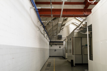 Stock photo of a long factory corridor with exposed pipes and industrial architecture. Perfect for...