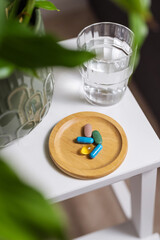 Colourful capsule pills with glass of water on the table, lifestyle shot