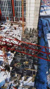 Drone flyover near the jib of a red tower crane at a winter construction site