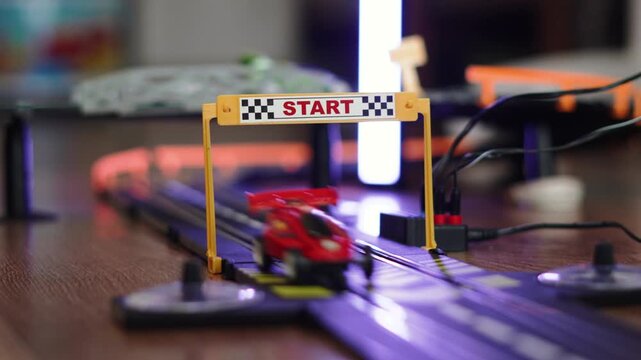 Toy cars drive on track under frame with inscription start. Entertainment and competition on remote controlled racing cars indoors close up.
