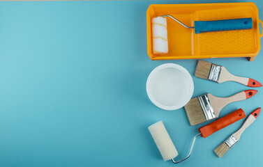 Flat lay of painting tools and bucket on cyan background for creative decorating and DIY renovation concept