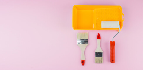 Painting set with tray, roller and brushes on pink background for DIY tools and interior work concept