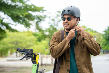Young Asian man ride scooter EV eco friendly transport. Sustainable save energy lifestyle. Commute and carbon neutral transportation. Asian tourist man put on helmet ride the scooter EV
