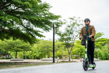 Young Asian man ride scooter EV eco friendly transport. Sustainable save energy lifestyle. Commute and carbon neutral transportation. Asian tourist man put on helmet ride the scooter EV