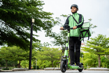 Rider food delivery man wearing green uniform and helmet ride the EV scooter delivery food service...