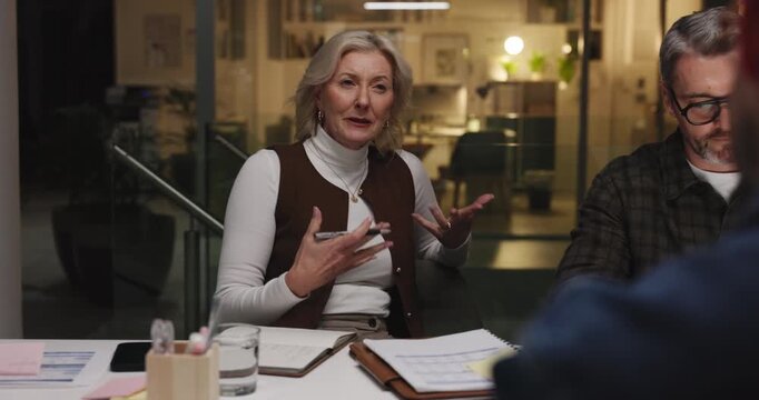 Team, night and business woman talk in office for story review, proposal feedback or idea. Meeting, overtime and group discussion with manager for copywriting, creative article or planning with notes