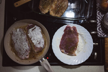 Frying meat rolled in flour on a pan