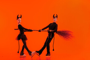 Young figure skaters performing in devil-themed Halloween costumes on ice