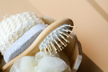 Wooden basket filled with sponge brush pumice and loofah arranged neatly on beige surface with...