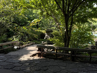 Shady park with a Shinto stone spirit house. Asian culture concept. Handmade phone photo, selective focus, harsh sunlight, non AI