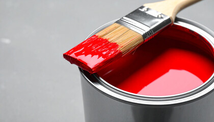 Open metallic can with vibrant red paint and paintbrush resting on rim. Creativity, inspiration.