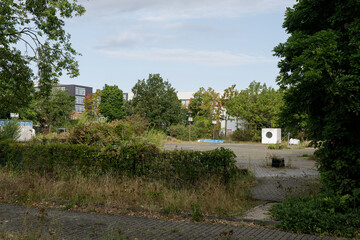 Fototapeta premium Photo depicts an overgrown, abandoned lot possibly a former playground, situated near urban buildings. Hints of neglect and nature reclaiming the space.