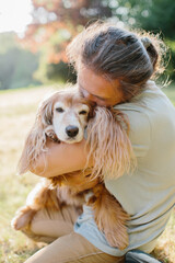 Woman embracing cocker spaniel with affection in green park
