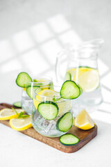 Cucumber lemon water with mint on wooden board in sunlight on white table