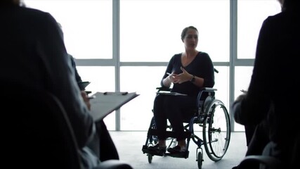 Wheelchair user leading business presentation in modern office meeting room - Powered by Adobe