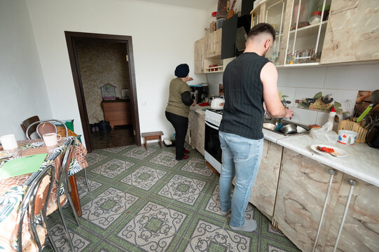 Two individuals engaged in cooking and cleaning in a cozy kitchen setting, creating a warm atmosphere filled with daily life activities, showcasing the harmony of shared moments