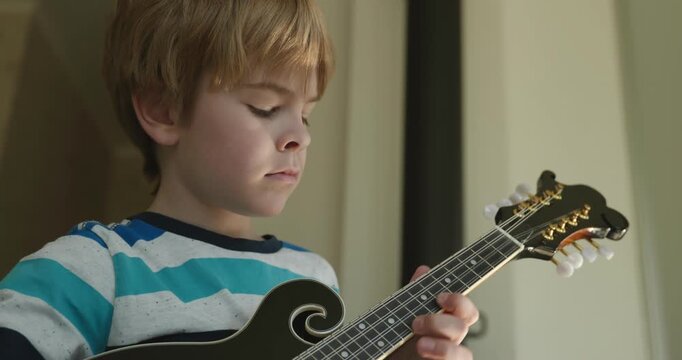 Caucasian Kid Play Mandolin at Home. European Boy Practice Music 4K 10-bit